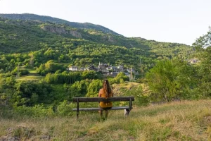 Beautiful shot of a woman sitting on the bench facing a mountain landscape
