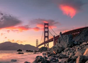 Golden Gate Bridge on body of water near rock formations during sunset in San Francisco, California