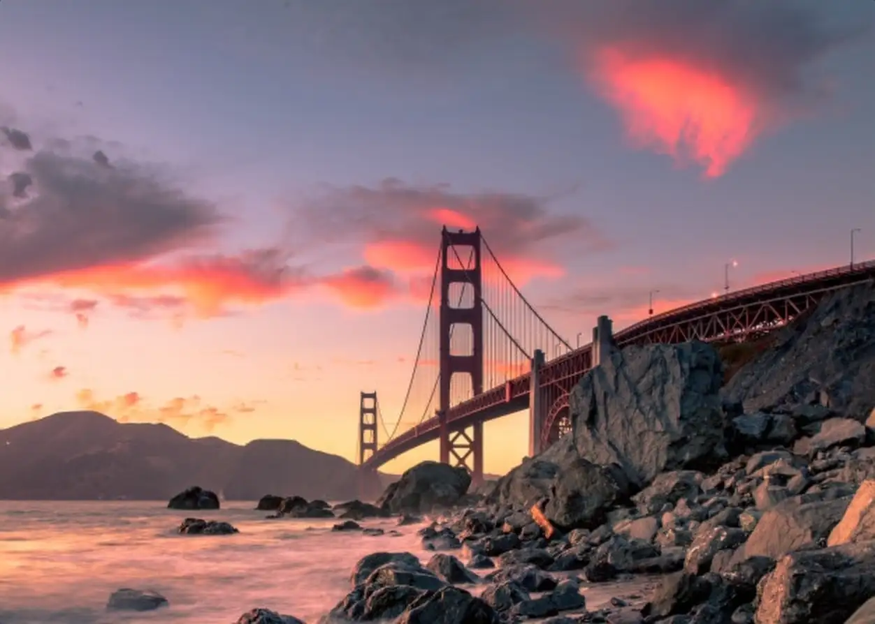 Golden Gate Bridge on body of water near rock formations during sunset in San Francisco, California